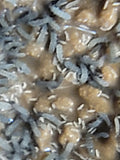 Close-up of brown, uneven chunks dusted with rice-shaped, gray and white shreds. Blurred Blue Springtails (Proistoma minuta) from I Heart Bugs, part of a clean-up crew, can be seen in this slightly out-of-focus image.