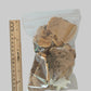 A clear plastic bag containing dried, irregularly shaped brown mushrooms, shown next to a wooden ruler for scale on a plain light background.