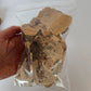 A clear plastic bag containing dried, irregularly shaped brown mushrooms
