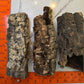 Three rough, cylindrical Small Cork Bark Rounds by IHEARTBUGS, INC. with varied textures and lichen rest on a white surface beside two orange rulers. Each virgin cork bark piece measures about 6–7 inches—ideal for bioactive enclosures.